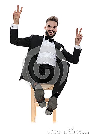 Businessman sitting and leaning back happy making victory sign Stock Photo