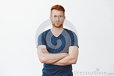 Good-looking european businessman with ginger hair and bristle in cool transparent glasses, crossing fingers on chest Stock Photo