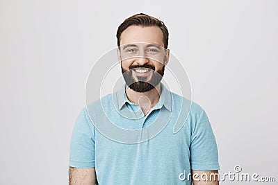 Good-looking european male adult with beard and moustache smiling broadly over gray background. Boyfriend stand behind Stock Photo