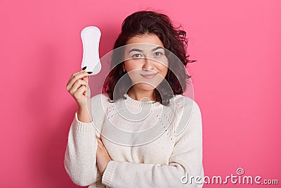 Good looking feminine girl holds clean sanitary napkin, has menstrual cycle, happy to have good women health, female with dark Stock Photo