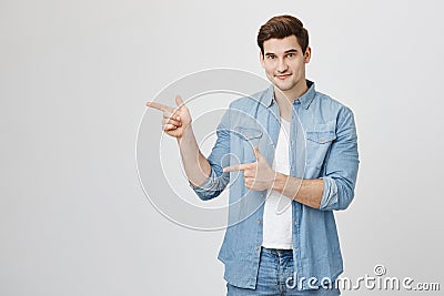 Good-looking handsome european guy with trendy haircut and sincere smile pointing index fingers, doing gun gesture Stock Photo