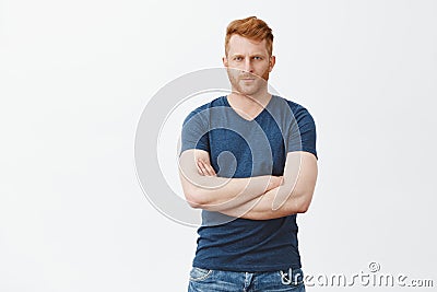 Good-looking serious male bodyguard with red hair and bristle, frowning, looking from under forehead strict at camera Stock Photo