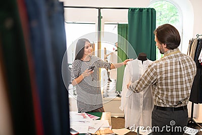 Good-looking talented fashion designer getting measurements of a dress Stock Photo