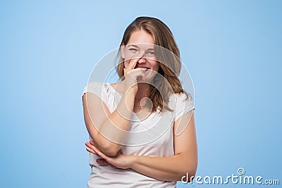 Good looking young european female giggles joyfully, covers mouth as tries stop laughing, wears casual white t shirt Stock Photo