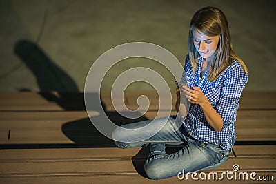 Good news. Beautiful young girl checks something on her smart phone and smiles absent-mindedly. Stock Photo