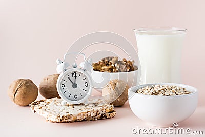 Good sleep. Alarm clock on the background of products for good falling asleep - milk, walnuts, oatmeal crispbread on a pink Stock Photo