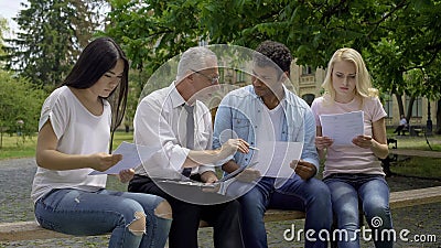 Good teacher giving additional tasks to multiracial students in university park Stock Photo