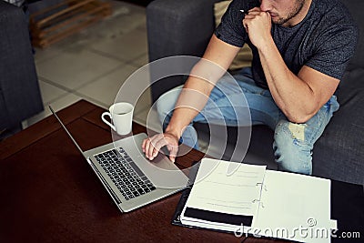 Good things come to those who work. Shot of an unidentifiable young man using his laptop to work from home. Stock Photo