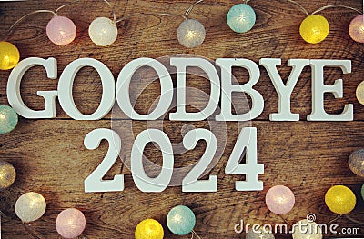 Goodbye 2024 alphabet letters and LED cotton ball decoration on wooden background Stock Photo