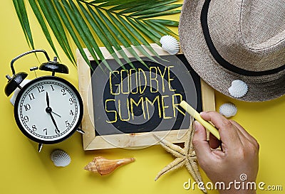 Goodbye Summer Text. Hand Holding Yellow Chalk and Blackboard Room for Text. Flat Lay Summer Beach Accessories Stock Photo