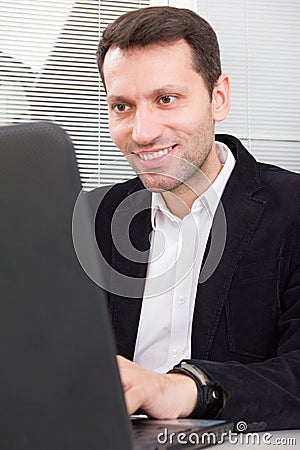 Goodlooking smiling business man sitting at table at home or of Stock Photo