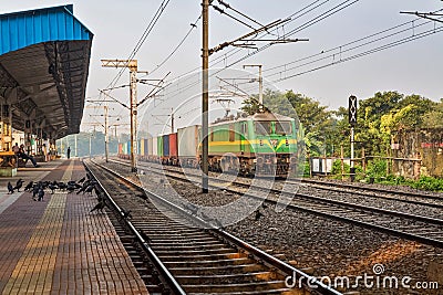 Goods train passes a deserted Indian railway station. Stock Photo