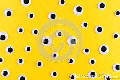 Googly plastic eyes pattern on yellow backgroud. Flat lay Stock Photo