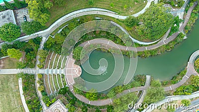 A gorgeous aerial shot of a silky green lake with a water fountain in the middle of the water surrounded by lush green trees Stock Photo