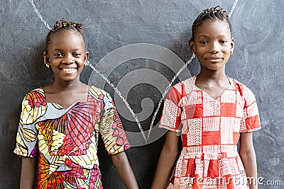 Gorgeous African Sisters Posing, Smiling and Laughing Happy in Front of Blackboard at School Stock Photo