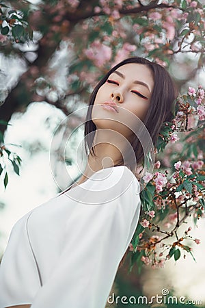 Asian woman outdoors on spring against flower blossom Stock Photo