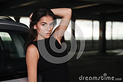 Gorgeous beautiful woman in black dress standing on car parking Stock Photo