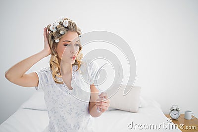 Gorgeous blonde wearing hair curlers kissing while looking at he Stock Photo