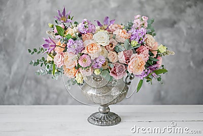 Gorgeous bouquet of different flowers. floral arrangement in vintage metal vase. table setting. lilac and peach color Stock Photo