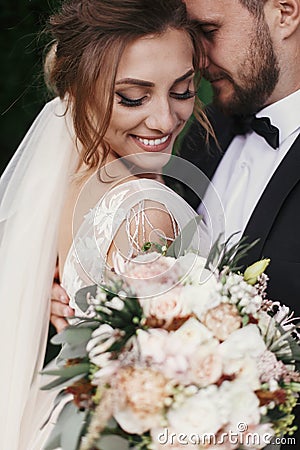 Gorgeous bride and stylish groom gently hugging and smiling on b Stock Photo