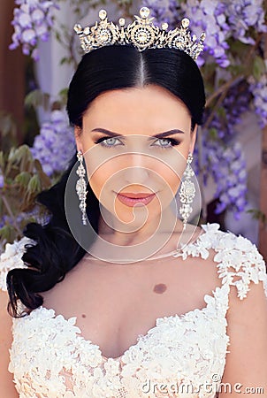 Gorgeous bride in wedding dress and crown posing in blossom summer garden Stock Photo