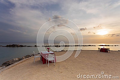 Gorgeous colorful view of sunset on Curacao island. Beautiful view of tables covered with white cloth on coast of Atlantic ocean. Stock Photo