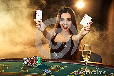 Gorgeous young woman sitting at poker table with glass of champagne Stock Photo