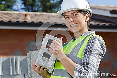 gorgeous female bricklayer holding concrete block Stock Photo