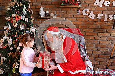 Little girl comes to Santa Claus, presents New Year gift and hug Stock Photo