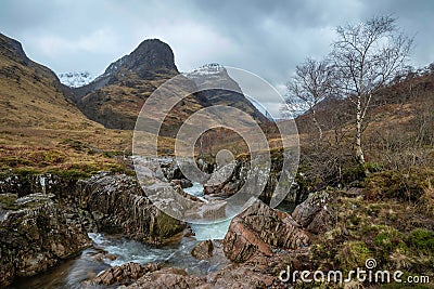 Gorgeous landscape image of vibrant River Coe flowing beneath snowcapped mountains in Scottish Highlands Stock Photo