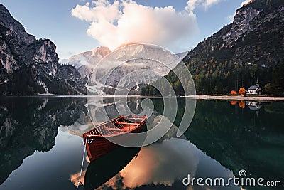 Gorgeous landscape. Wooden boat on the crystal lake with majestic mountain behind. Reflection in the water. Chapel is on Stock Photo