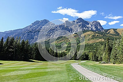 Gorgeous par 4 on a golf course surrounded by forest and big mountains in the background, on a beautiful sunny day in Kananaskis, Stock Photo