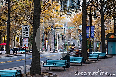 A gorgeous shot of an autumn landscape in the city with rows of blue benches surrounded by gorgeous autumn colored trees Editorial Stock Photo