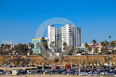 A gorgeous shot of beach front hotels with lush green palm trees and parked cars near a sandy beach with gorgeous clear blue sky Editorial Stock Photo