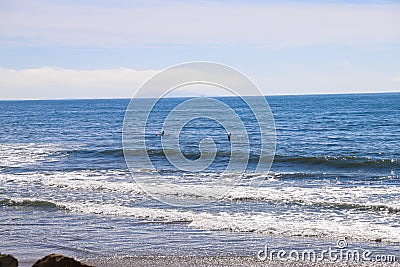 A gorgeous shot of the beach near a long stretch of road with cars and large rocks along the beach, vast blue ocean water Stock Photo