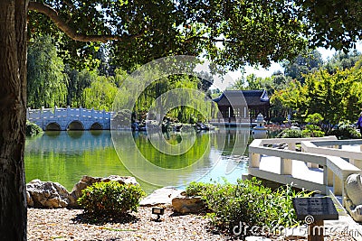 A gorgeous shot of the stone bridge with 3 circles over the green lake surrounded by lush green and autumn colored trees Stock Photo