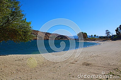 A gorgeous shot of the vast blue water and lush green foliage on the shores of Castaic Lake Stock Photo