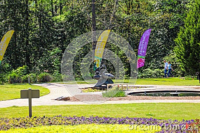 A gorgeous summer landscape in the garden with lush green trees, grass and plants and colorful flowers with people walking Editorial Stock Photo