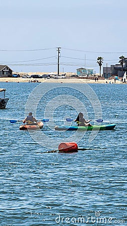 a gorgeous summer landscape at Horny Corner Beach with two women rowing colorful kayaks and people on the sandy beach Editorial Stock Photo