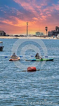 a gorgeous summer landscape at Horny Corner Beach with two women rowing colorful kayaks and people on the sandy beach Editorial Stock Photo