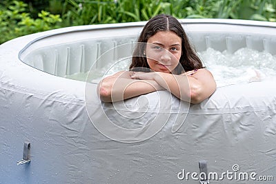 Gorgeous teenage girl with long, dark hair relaxes in the garden inflatable pool with jacuzzi Stock Photo