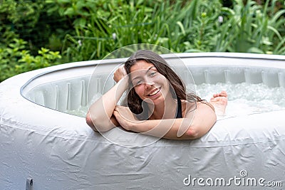 Gorgeous teenage girl with long, dark hair relaxes in the garden inflatable pool with jacuzzi Stock Photo