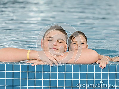 gorgeous view of teenage boy and little girl playing and relaxing in outdoor swimming pool Stock Photo