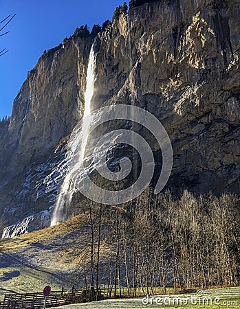 Gorgeous waterfall at famous Lauterbrunnen valley and Swiss Alps with sunlight reflection in winter season Stock Photo