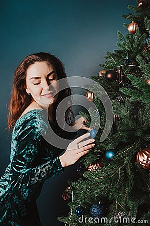 Gorgeous woman in a beautiful dress posing near Christmas tree. Seductive playful female portrait. New Year and Christmas Stock Photo