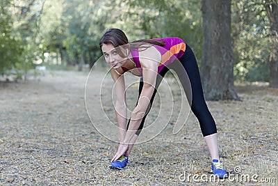 Gorgeous young slim woman makes gym in morning park. Side tilt, bright sportswear, white earphones, calmness and relax atmosphere, Stock Photo