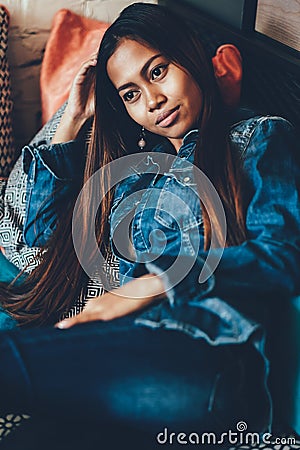 Gorgeous young woman in blue jeans laying on sofa with trow pillows Stock Photo