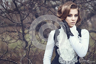 Gorgeous young woman with elegant Victorian hairstyle holding her hand in leather glove at her cheek Stock Photo