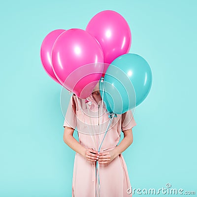 Gorgeous young woman in party outfit holding bunch of colourful balloons, isolated over pastel blue colored background. Birthday. Stock Photo