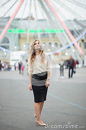 Gorgeus blonde woman in leather skirt posing on the ferris wheel background Stock Photo